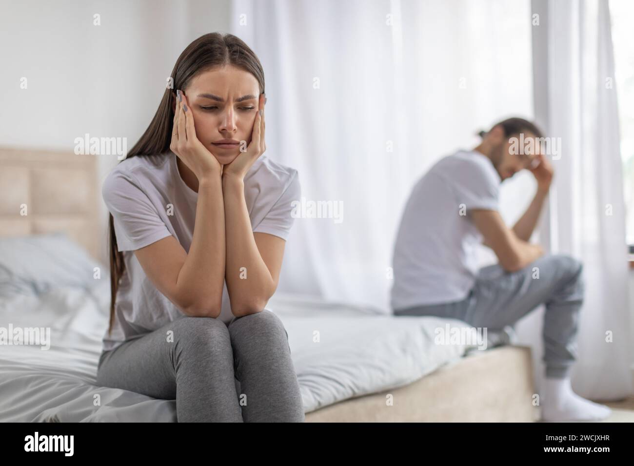 Enttäuschte Dame, die auf dem Bett sitzt, beleidigten Mann ignoriert, frustrierte Frau, die über Beziehungsprobleme nachdenkt, Stockfoto