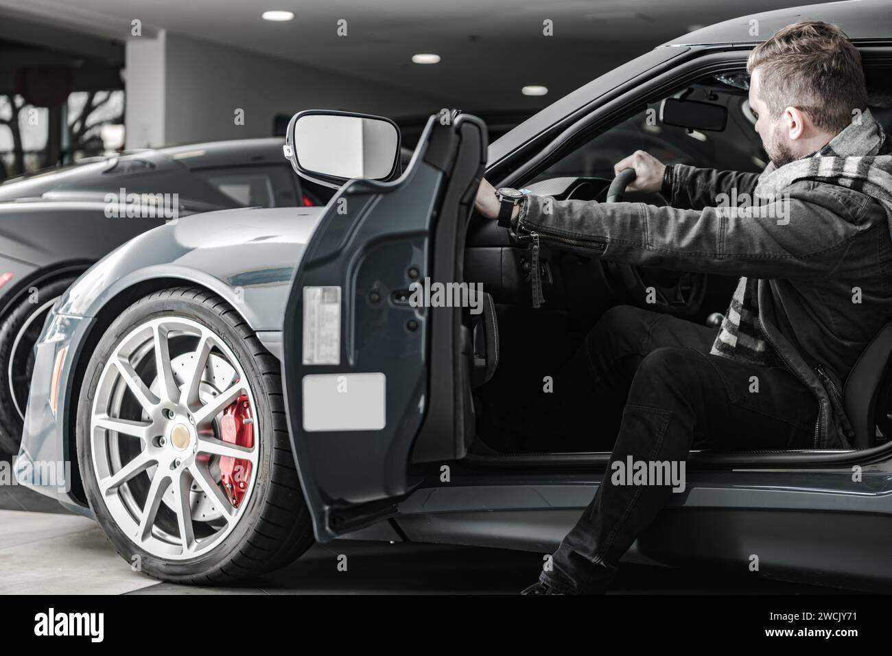 Kaukasischer Kunde in seinen 30ern kaufte exotische Autos in einem Händlerbetrieb. Thema Fahrzeugkauf. Stockfoto