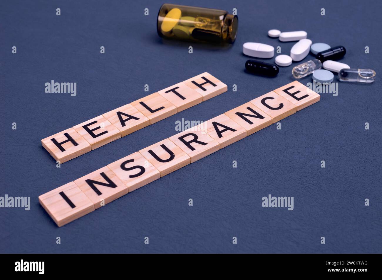 Krankenversicherungstext mit Pillen auf grauem Hintergrund. Krankenversicherung, Gesundheitsrisiko, Bezahlung für das Gesundheitskonzept. Stockfoto