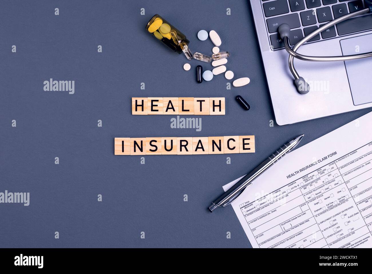 Krankenversicherungsformular Anspruch mit Laptop, Stethoskop und Pillen auf dem Tisch. Krankenversicherung, Gesundheitsrisiko, Bezahlung für das Gesundheitskonzept. Stockfoto