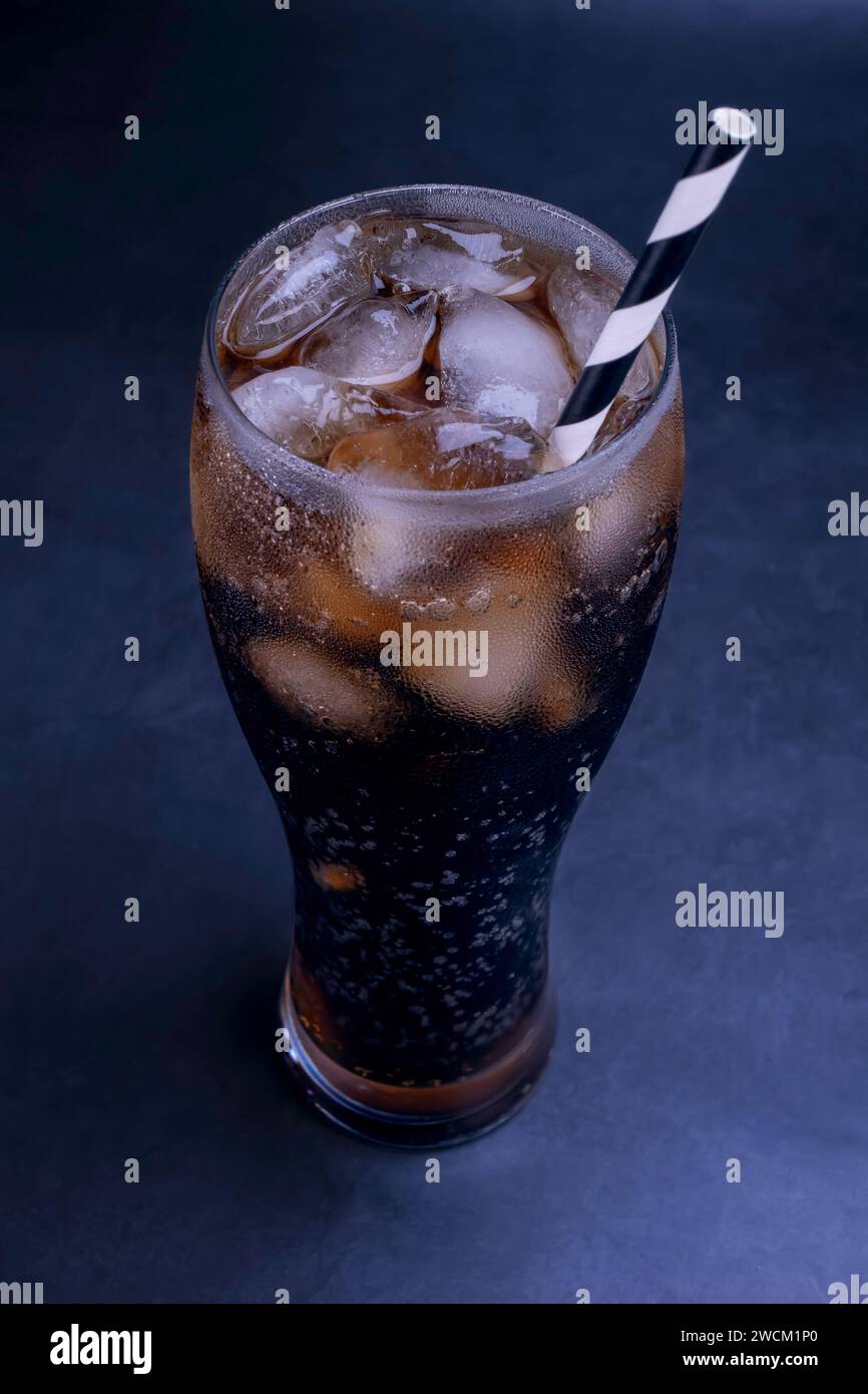 Kühles Glas Cola mit Eis, Blasen und Fizz. Frisches, kaltes Süßes mit Eiswürfeln. Cola-Glas mit Sommererfrischung auf Schwarz. Stockfoto