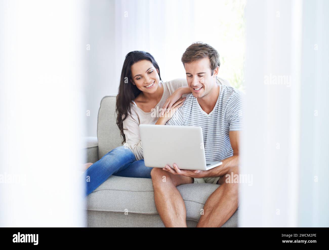 Paare, Laptop und Filme auf der Couch mit Liebe, Wohnzimmer und Wellness in der Ehe für Bindungen. Frau, Mann und Lächeln für die Beziehung Stockfoto