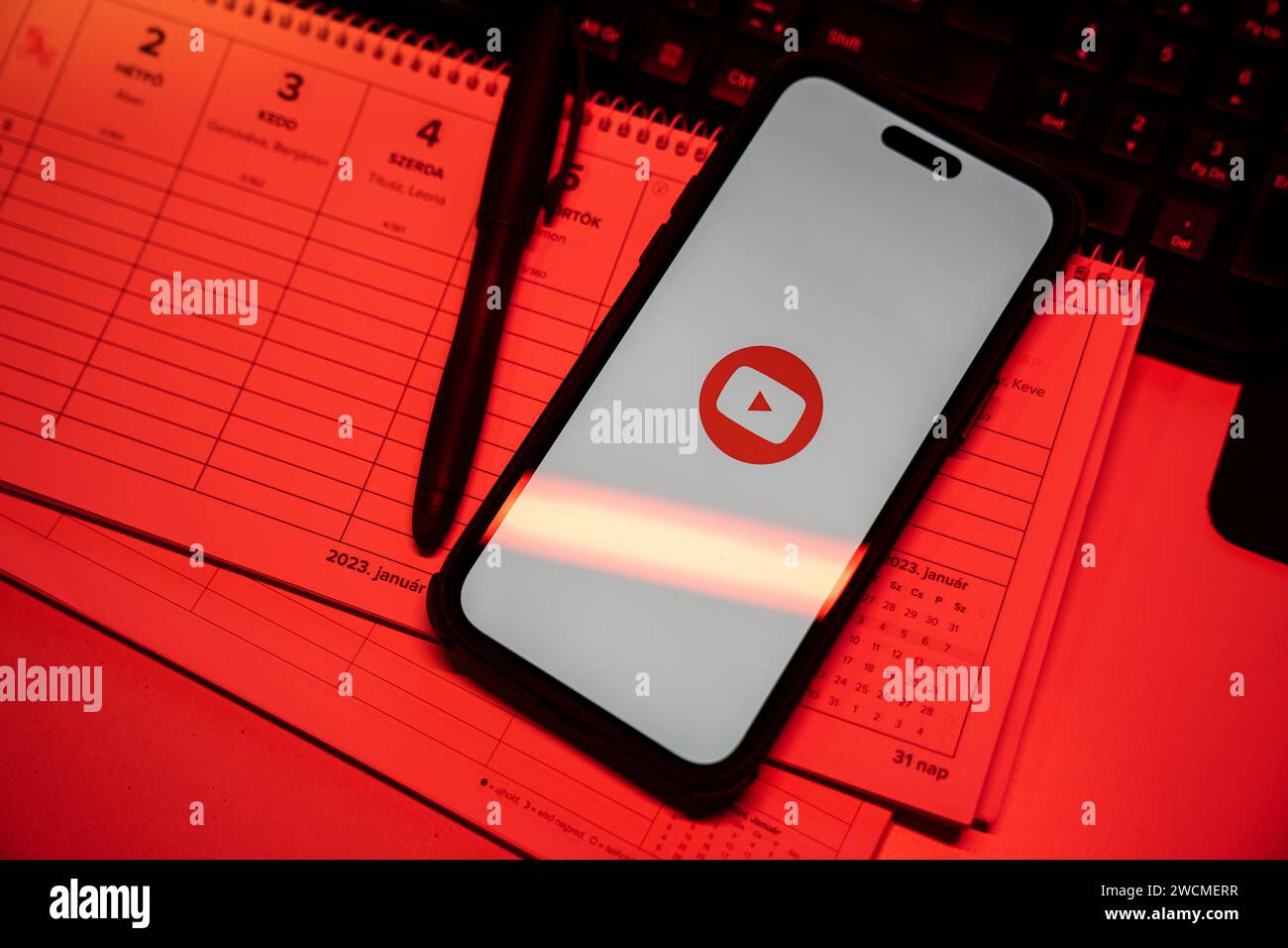 Apple iPhone 14 Pro Max Smartphone mit YOUTUBE Logo. YouTube ist eine Website zum Teilen von Videos. Schwaches grünes Stimmungslicht, in einer Videoumgebung im Büro. Stockfoto