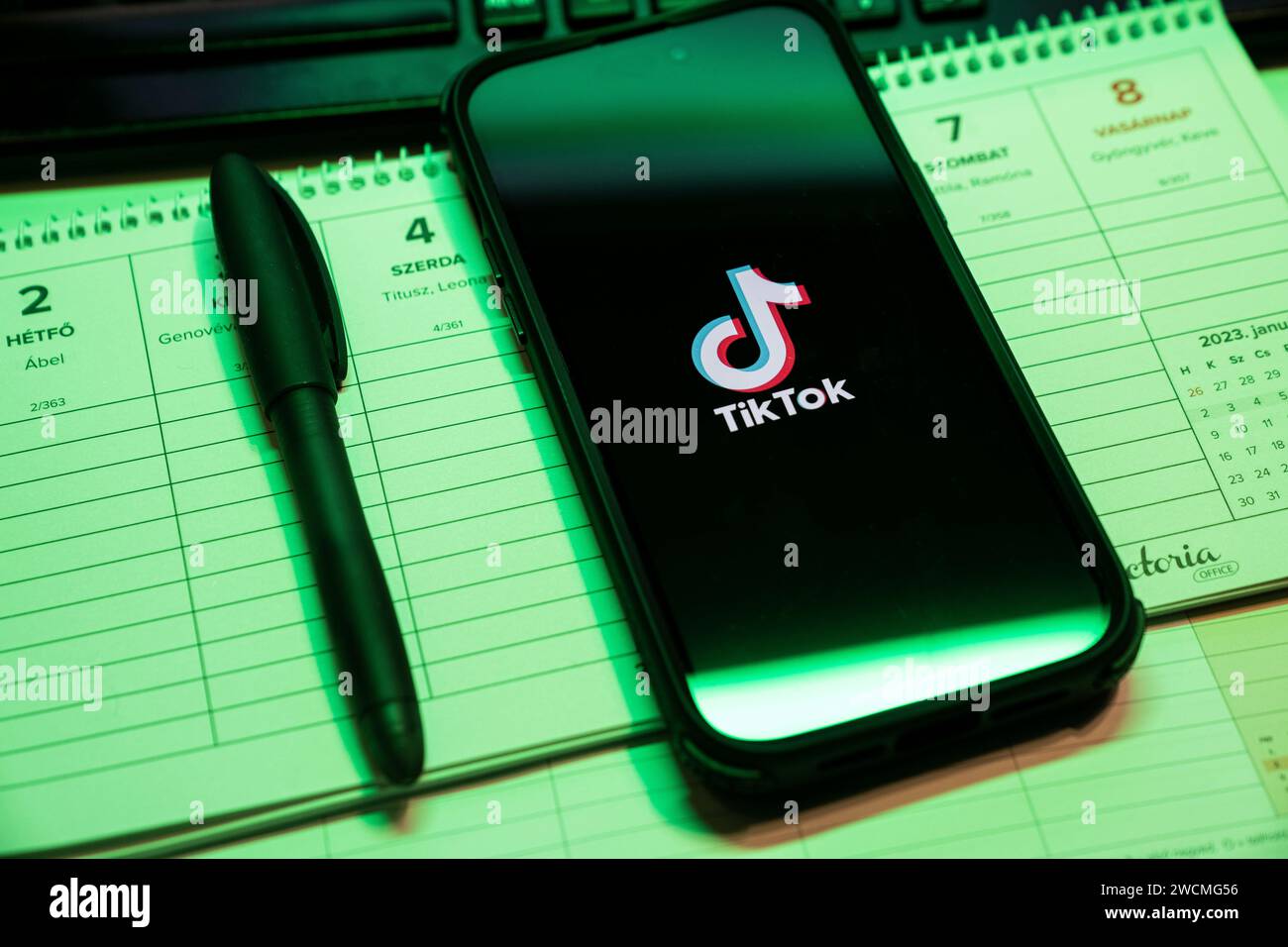Tik Tok Anwendung auf dem Bildschirm des Apple iPhone 14 Pro Max Smartphones auf der linken Hintergrundtabelle. Büroumgebung. Budapest, Ungarn. Nove Stockfoto
