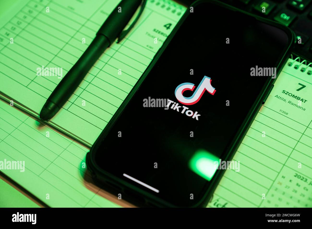 Tik Tok Anwendung auf dem Bildschirm des Apple iPhone 14 Pro Max Smartphones auf der linken Hintergrundtabelle. Büroumgebung. Budapest, Ungarn. Nove Stockfoto