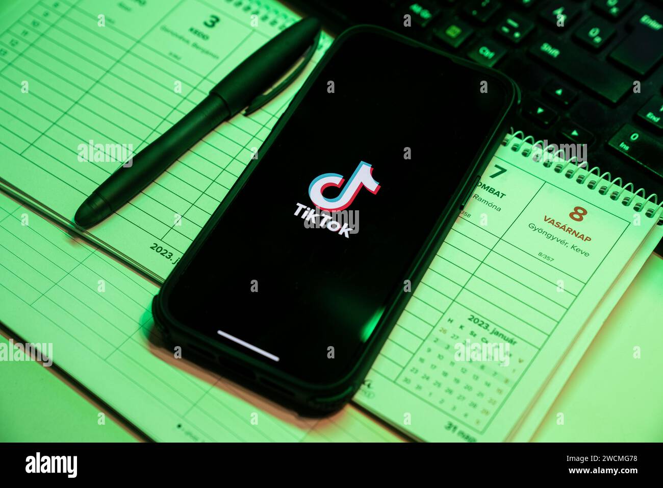 Tik Tok Anwendung auf dem Bildschirm des Apple iPhone 14 Pro Max Smartphones auf der linken Hintergrundtabelle. Büroumgebung. Budapest, Ungarn. Nove Stockfoto
