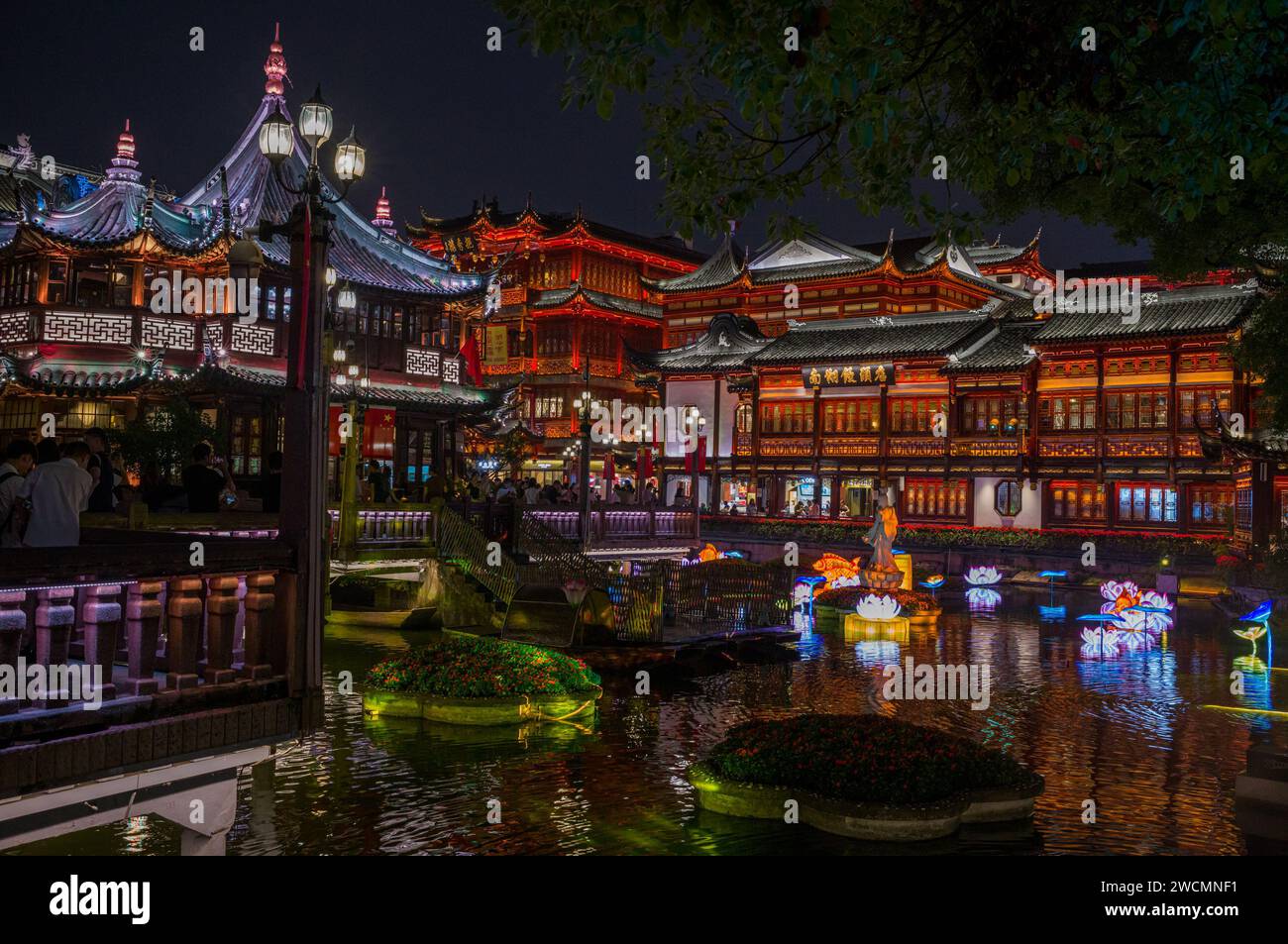 Ein majestätischer chinesischer Palast, beleuchtet gegen den Nachthimmel, in der Nähe eines friedlichen Sees in Shanghai Stockfoto
