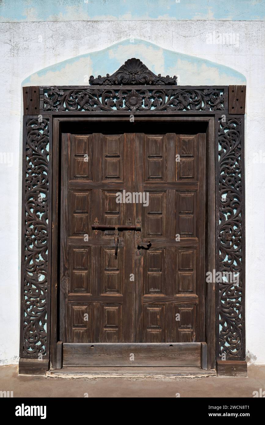 Alte braune Holztür mit einem Rahmen aus Blumenschmuck Stockfoto