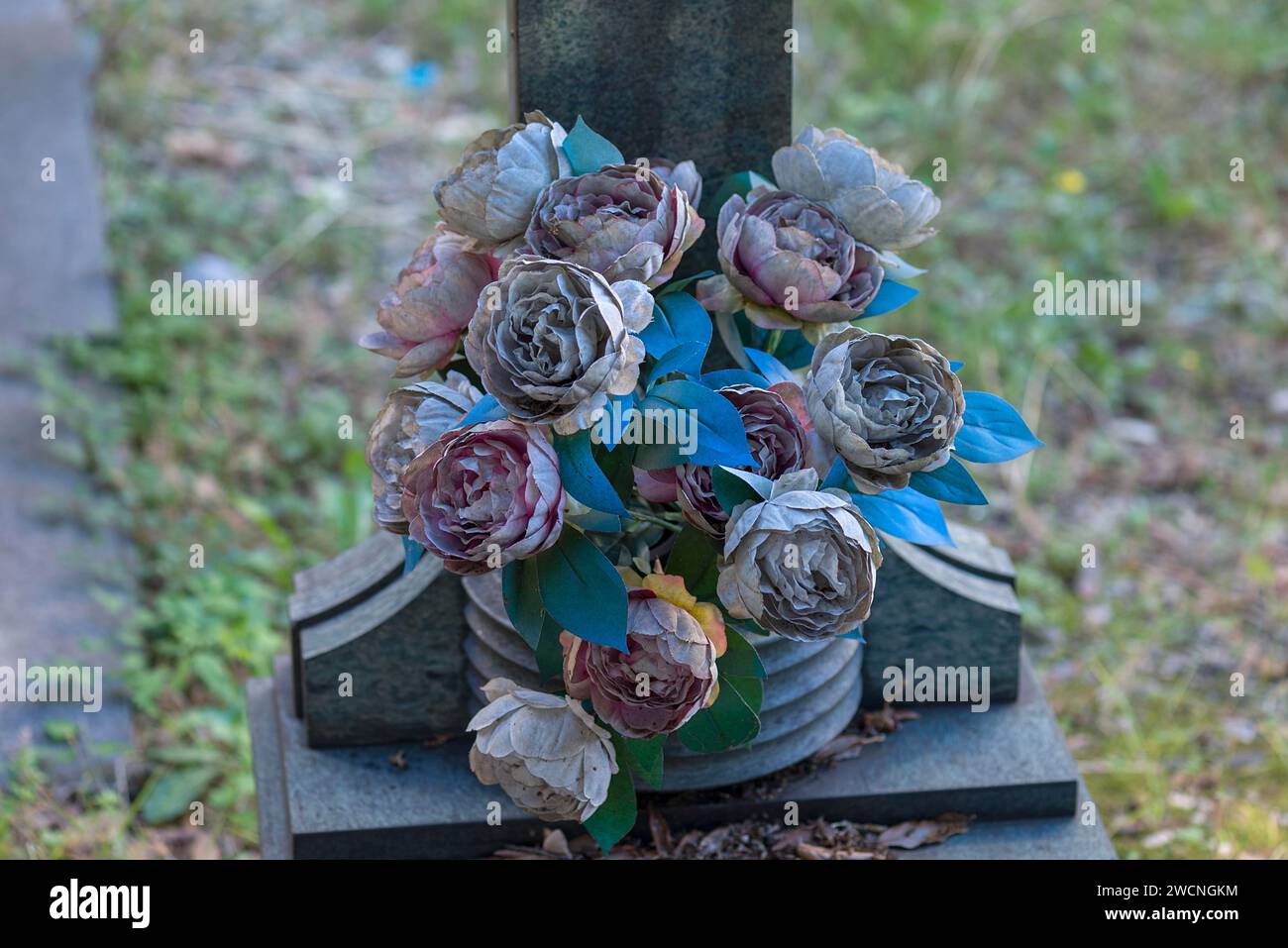Verblasste Plastikblumen auf einem Grab auf dem Monumentalfriedhof von Staglieno, Cimitero Monumentale di Staglieno, Piazzale Giovanni Battista Resasco, Genua Stockfoto