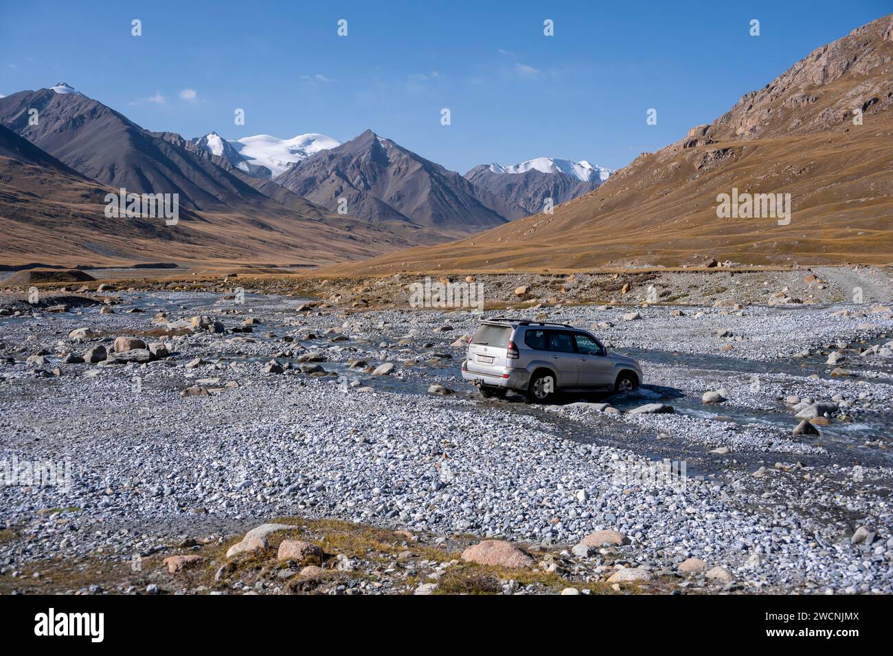 Geländewagen überquert einen Fluss im Burchan-Tal, Berglandschaft mit Gletschern und goldenen Wiesen, Terskey Ala-Too, Tien Shan Stockfoto