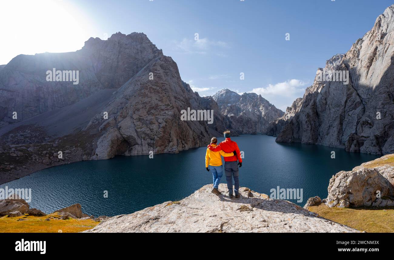 Paare am blauen Bergsee zwischen felsigen steilen Berggipfeln, Kol Suu Lake, Sary Beles Mountains, Naryn Province, Kirgisistan Stockfoto