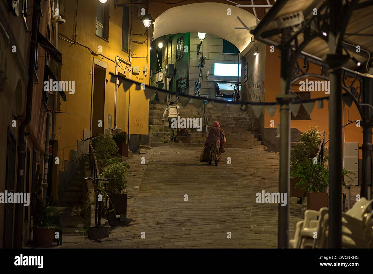 Zwei Bewohner mit Koffern, die abends von einer Reise nach Hause zurückkehren, Altstadt von Genua, Italien Stockfoto