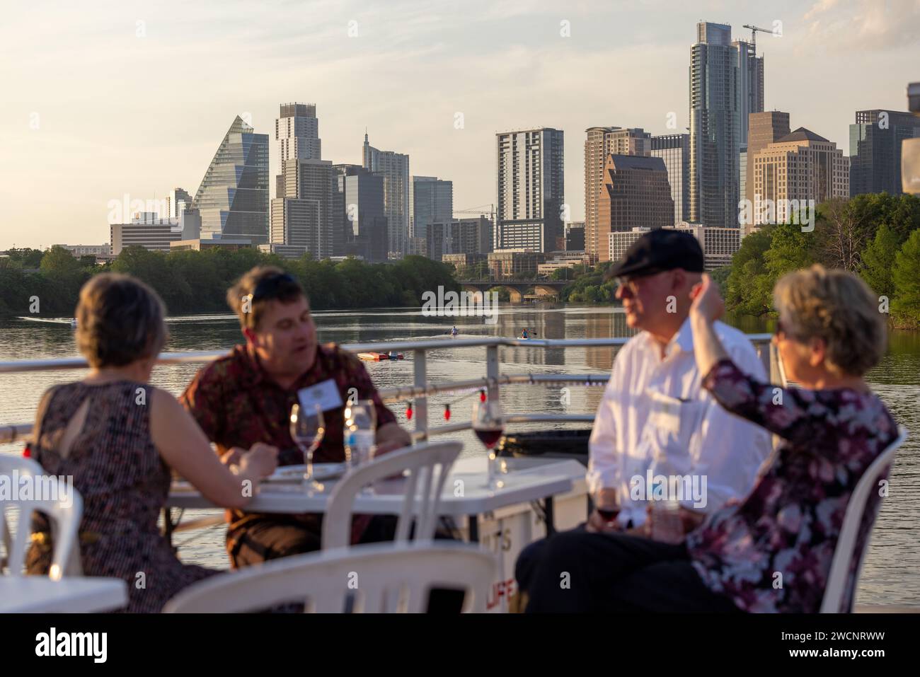 Eine Gruppe von Menschen genießt eine Mahlzeit am Fluss vor der Kulisse der Skyline der Stadt Stockfoto