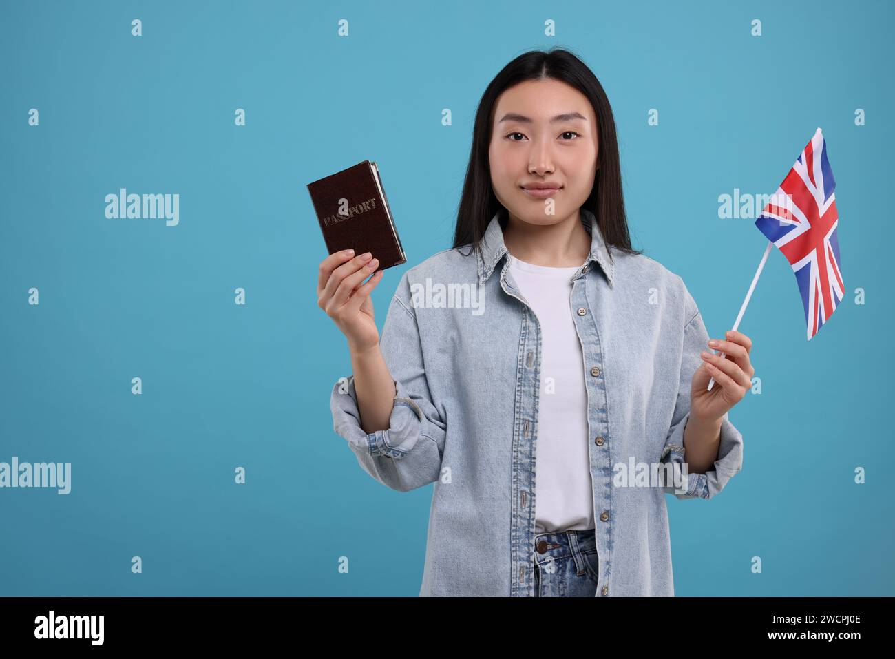 Einwanderung nach Großbritannien. Frau mit Pass und Flagge auf hellblauem Hintergrund, Platz für Text Stockfoto