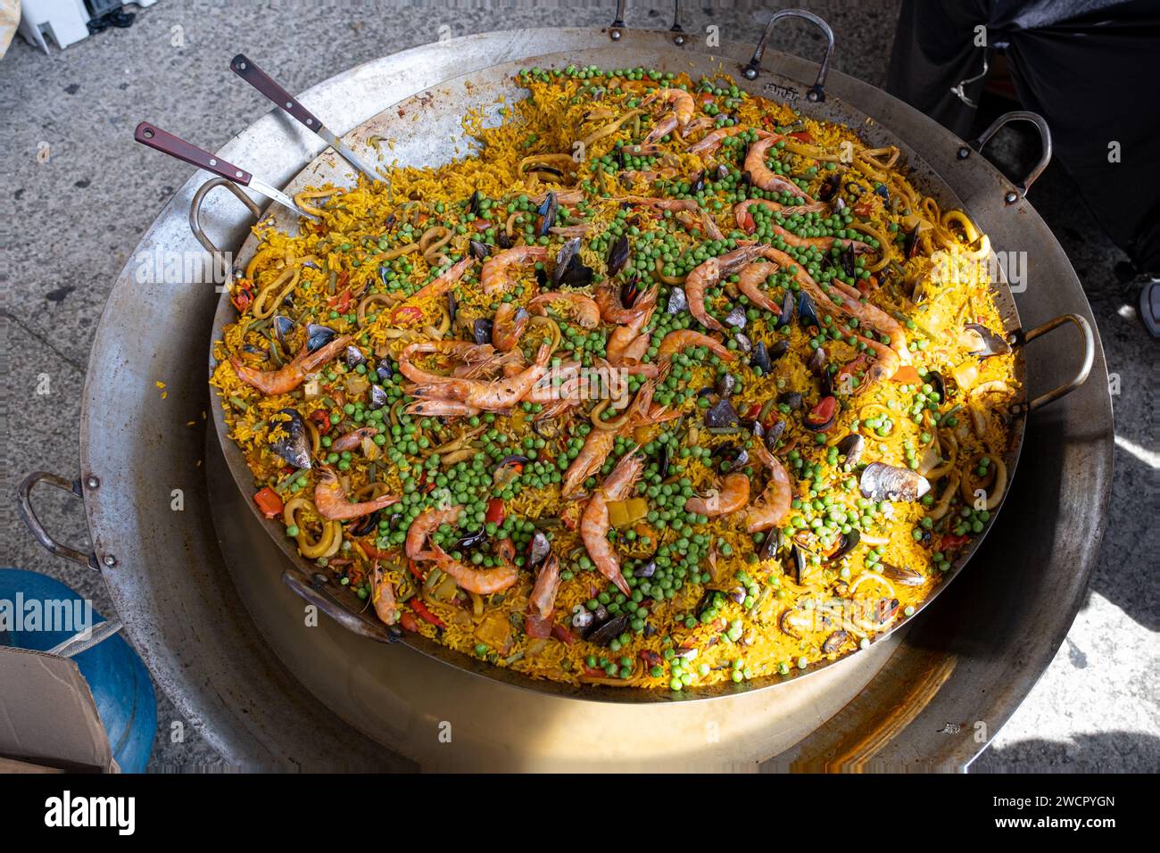 Mexikanische Paella mit verschiedenen Zutaten (Reis, Garnelen, Erbsen, Schalentiere und Tomaten), die in einem großen Wok 4 hergestellt werden. Stockfoto