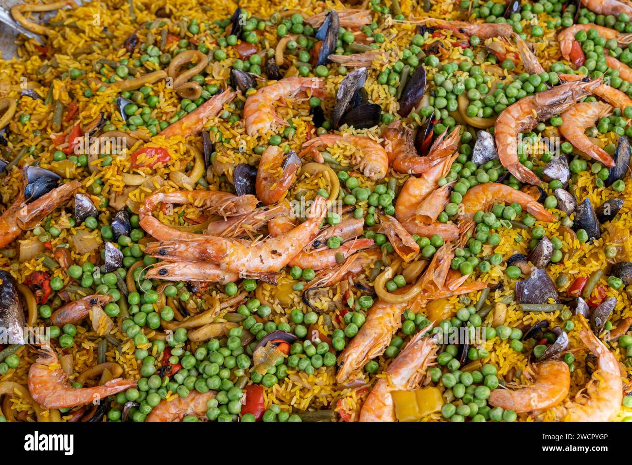 Mexikanische Paella mit verschiedenen Zutaten (Reis, Garnelen, Erbsen, Schalentiere und Tomaten), die in einem großen Wok 5 hergestellt werden. Stockfoto