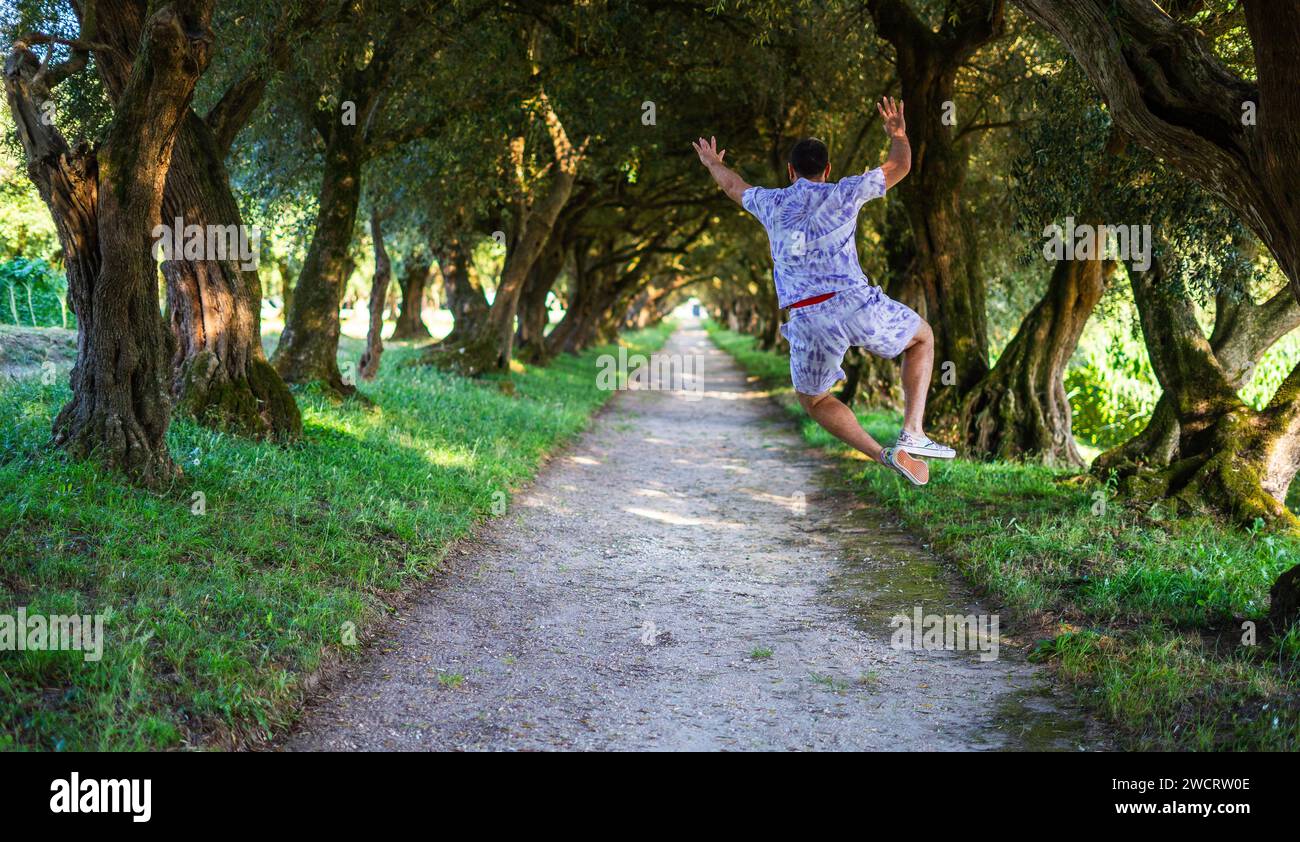 Glücklicher junger kaukasischer Mann, der vor Freude im Wald springt. Sommerferien, Freude, glücklich. Stockfoto