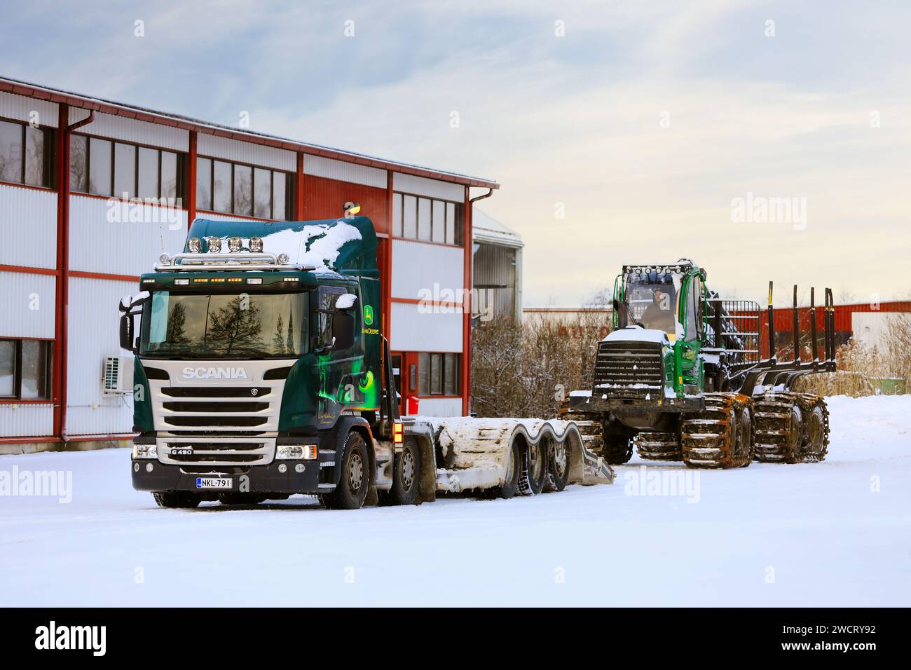 Verladung des John Deere 1210E Forstförderers auf den Scania G490 Lkw-Anhänger für den Transport an einem Wintertag. Salo, Finnland. Dezember 2023. Stockfoto