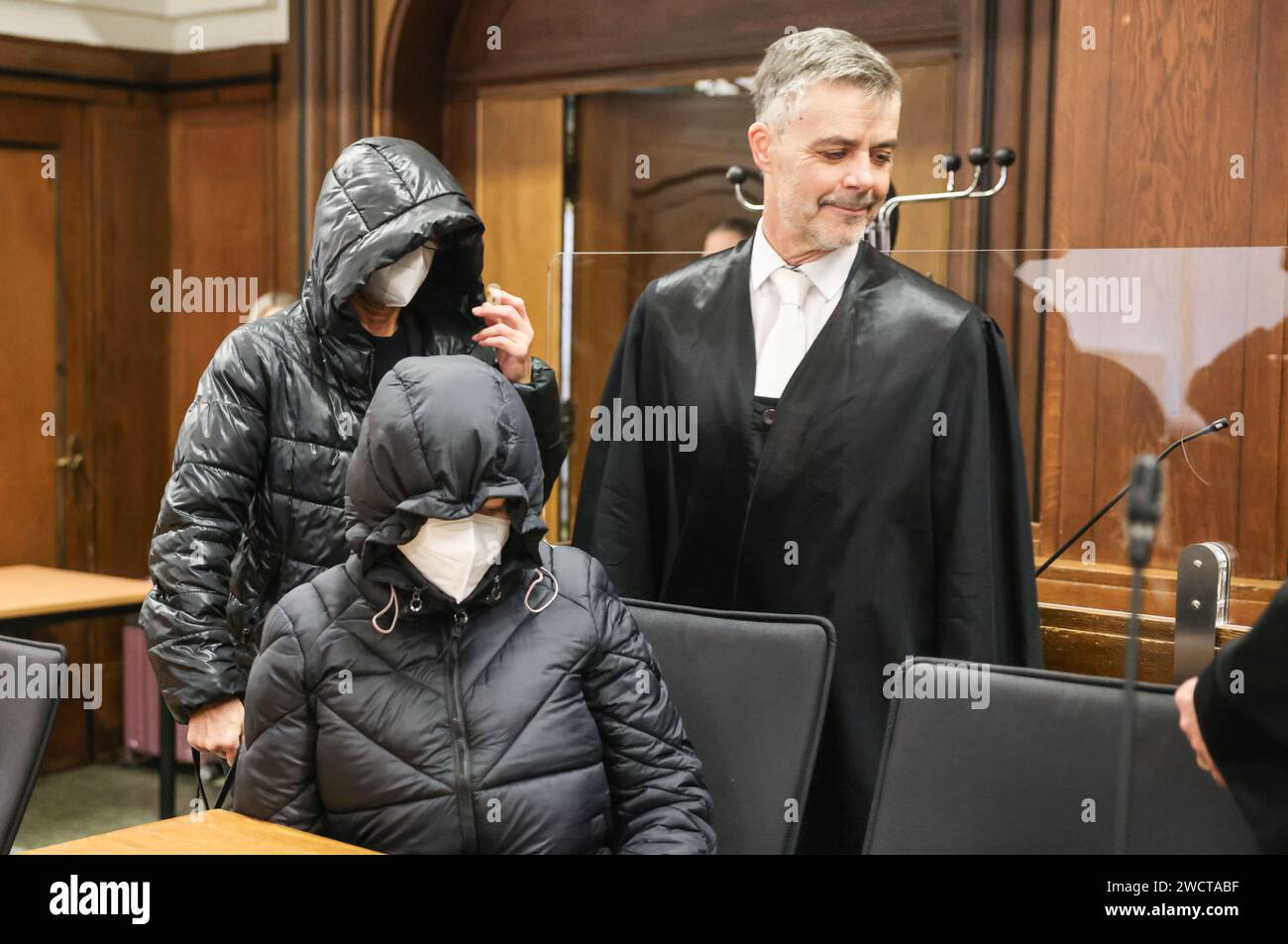 17. Januar 2024, Nordrhein-Westfalen, Mönchengladbach: Die beiden Angeklagten tragen Hauben auf dem Kopf, als sie mit Rechtsanwalt Marius Kuschka (r) in den Gerichtssaal eintreten. Zwei Lehrer stehen vor Gericht am Amtsgericht Mönchengladbach wegen mutmaßlichen Totschlags. Die Lehrer begleiteten im Juni 2019 eine Schulreise nach London, bei der ein 13-jähriger Schüler an Diabetes starb. Foto: Oliver Berg/dpa Stockfoto