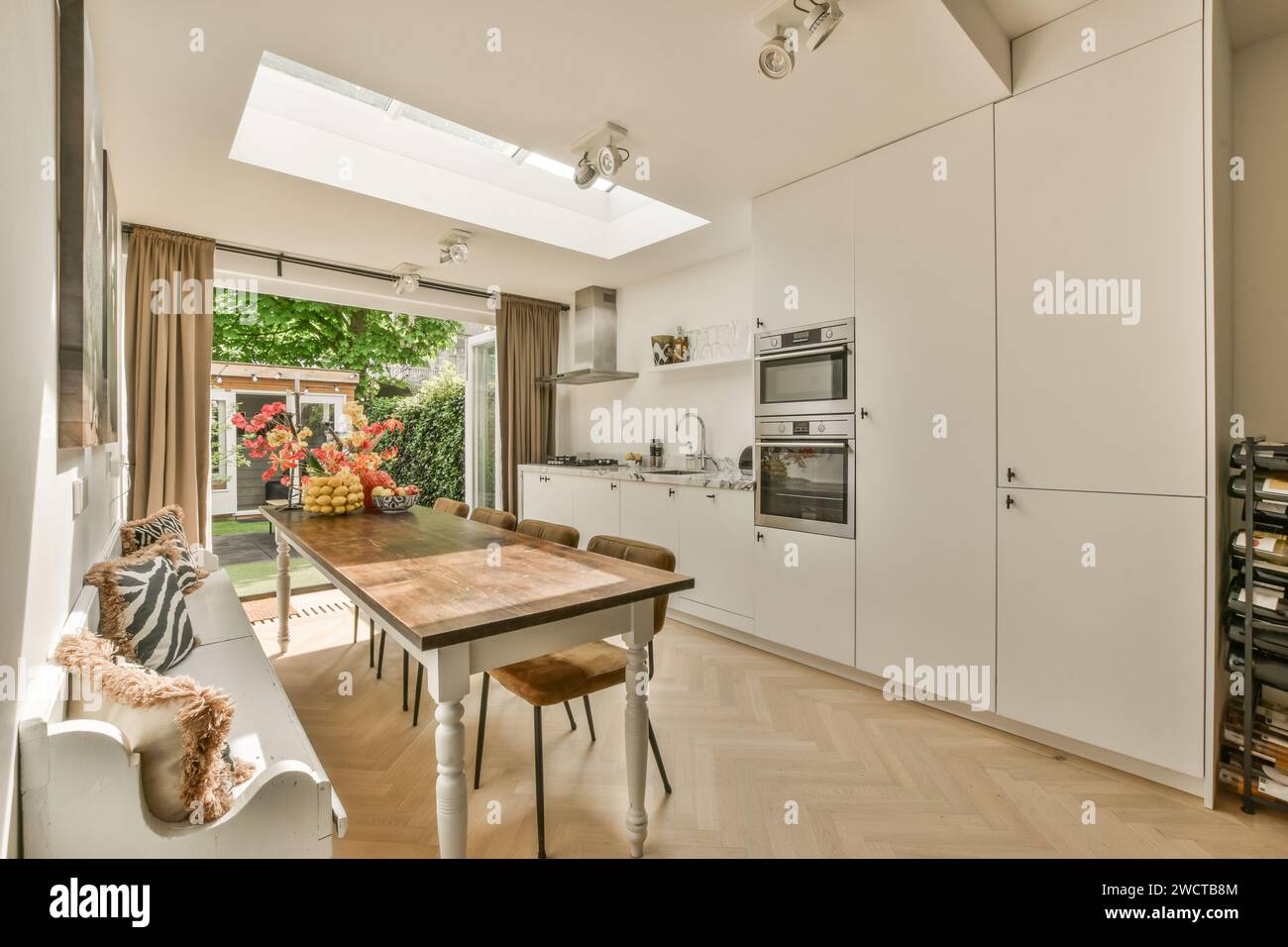 Esszimmer aus Holz und Stühle, die vor der Küche durch ein großes Fenster in einem luxuriösen, modernen Apartment angeordnet sind Stockfoto