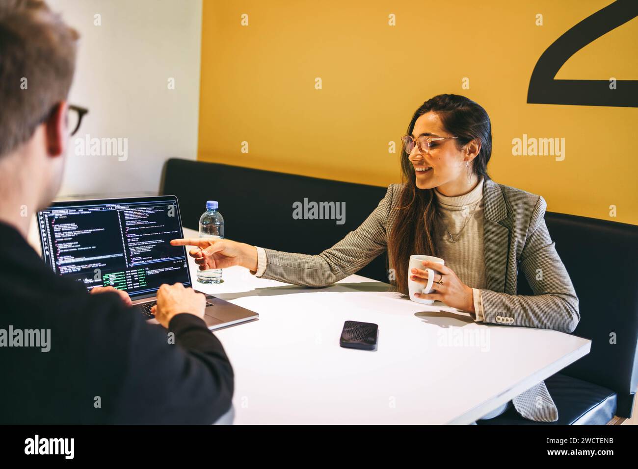 Technische Experten arbeiten in einem modernen Büro zusammen, programmieren Software und diskutieren über Entwicklung. Sie arbeiten Remote, kodieren und arbeiten zusammen, cr Stockfoto