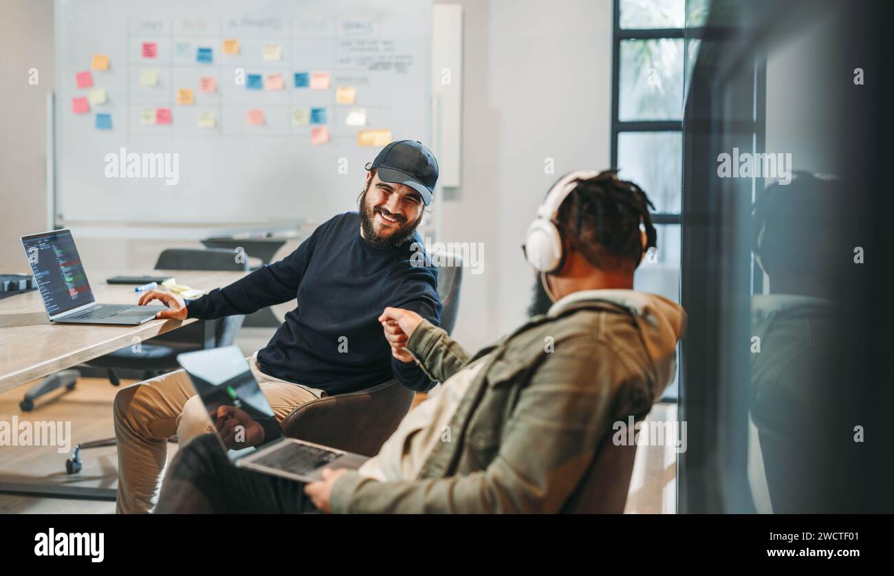 Zwei Männer feiern ihre erfolgreichen Ideen. Kodieren und Programmieren zusammen, lächeln und arbeiten an der Softwareentwicklung. Ein glückliches, kreatives Team in A Stockfoto