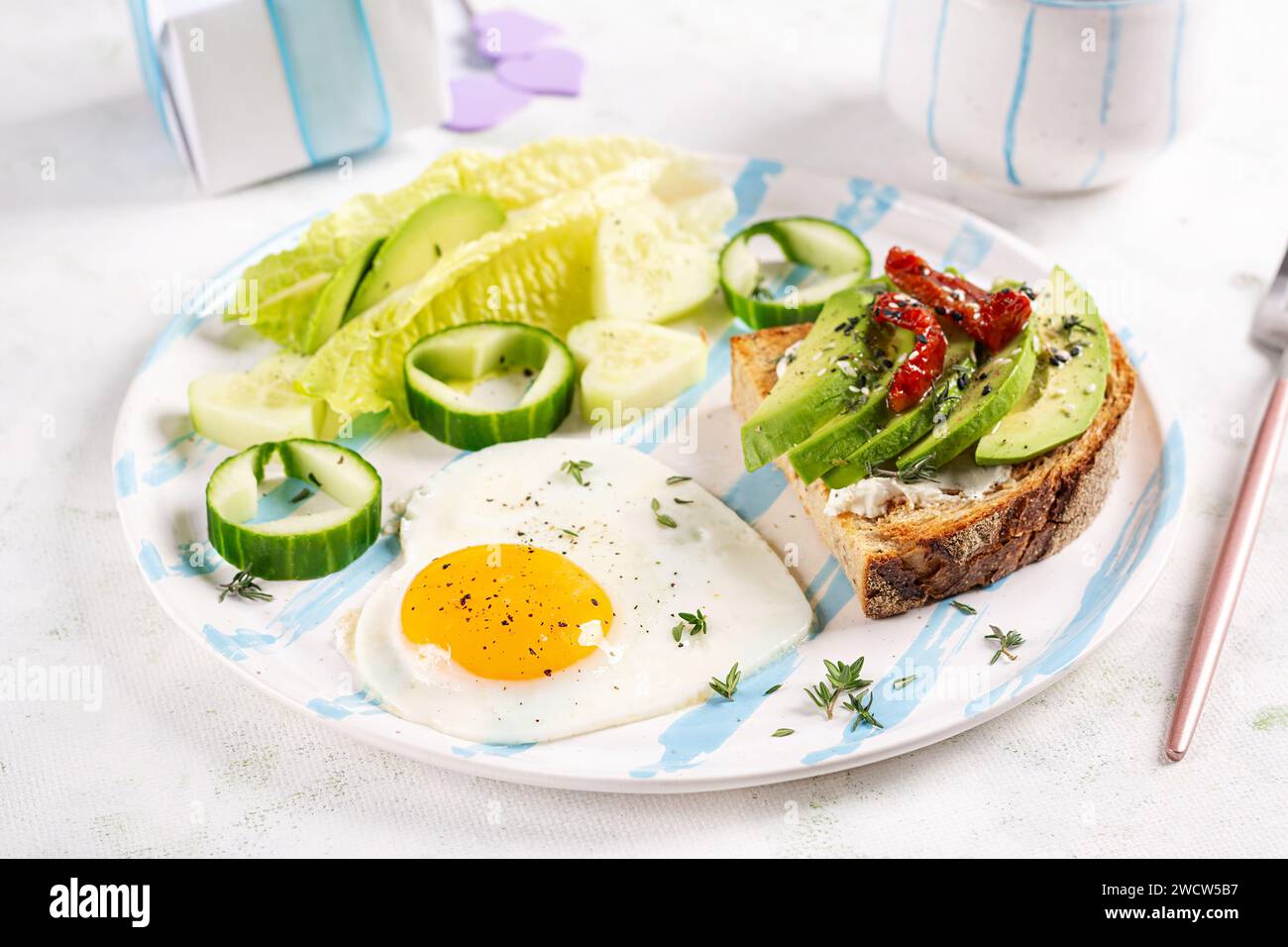 Romantisches Frühstück zum Valentinstag. Spiegelei und Toast mit Avocado und Frischkäse. Stockfoto