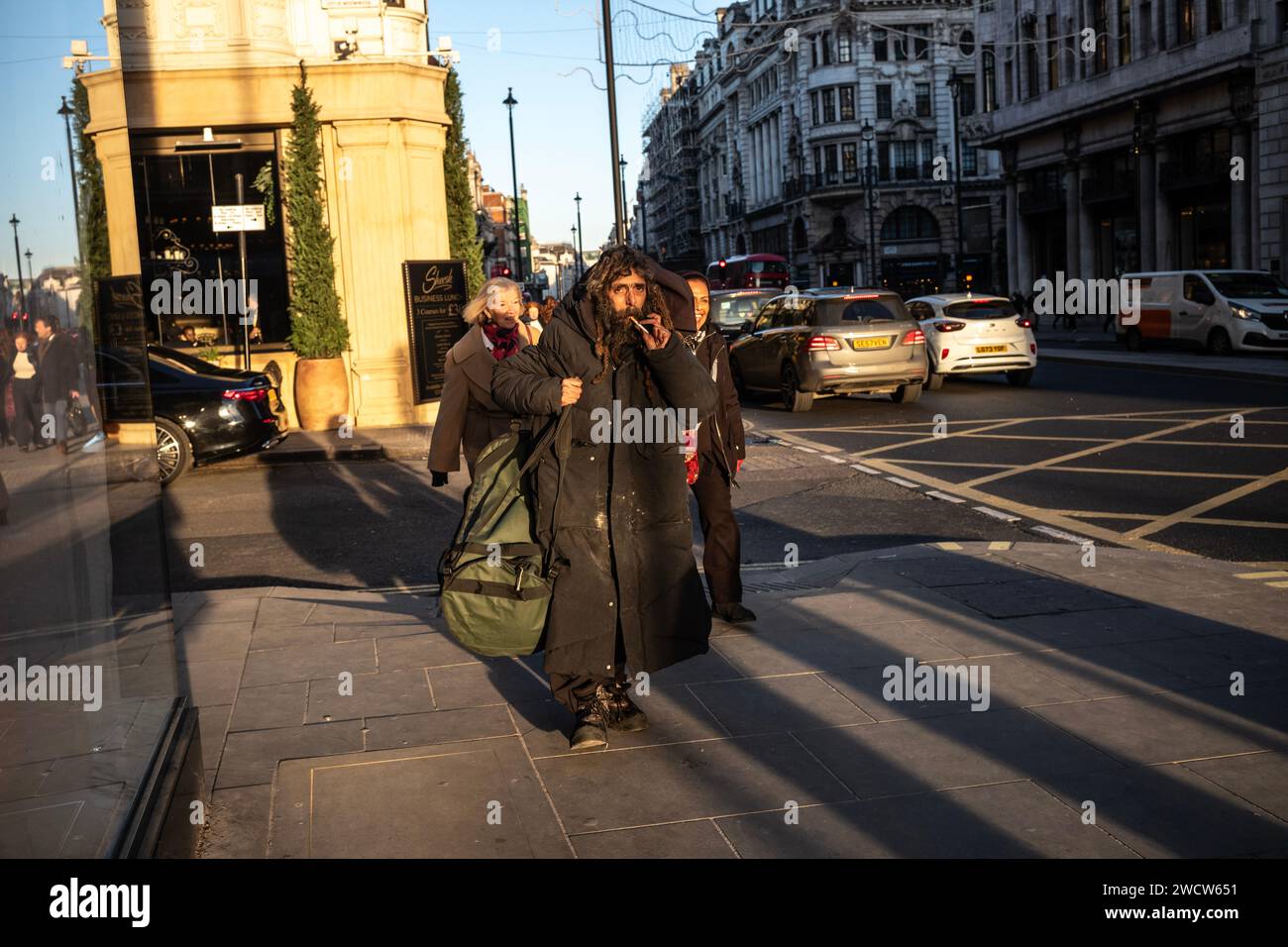 Ein Tramper mit dickem Wintermantel geht den Piccadilly hinunter in Richtung Marble Arch, London, England, Großbritannien Stockfoto