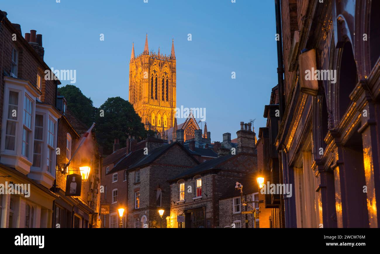 Lincoln, Lincolnshire, England. Blick auf die Straße zum beleuchteten zentralen Turm der Lincoln Cathedral in der Abenddämmerung. Stockfoto