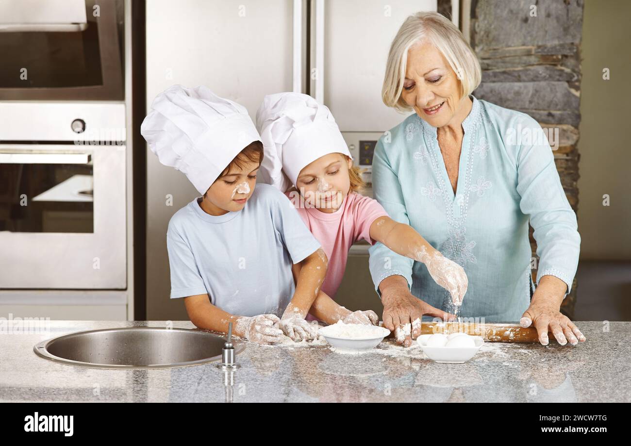 Großmutter der Familie backt weihnachtskekse mit Enkeln zusammen in ihrer Küche Stockfoto