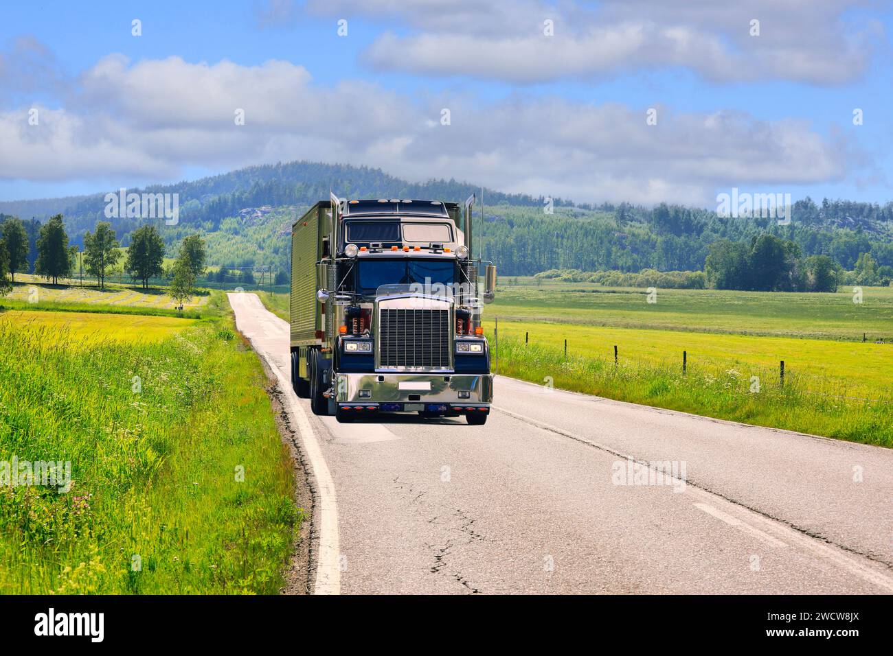 Klassischer amerikanischer Lkw-Auflieger auf ländlicher Straße durch wunderschöne Sommerlandschaft an einem sonnigen Tag. Stockfoto