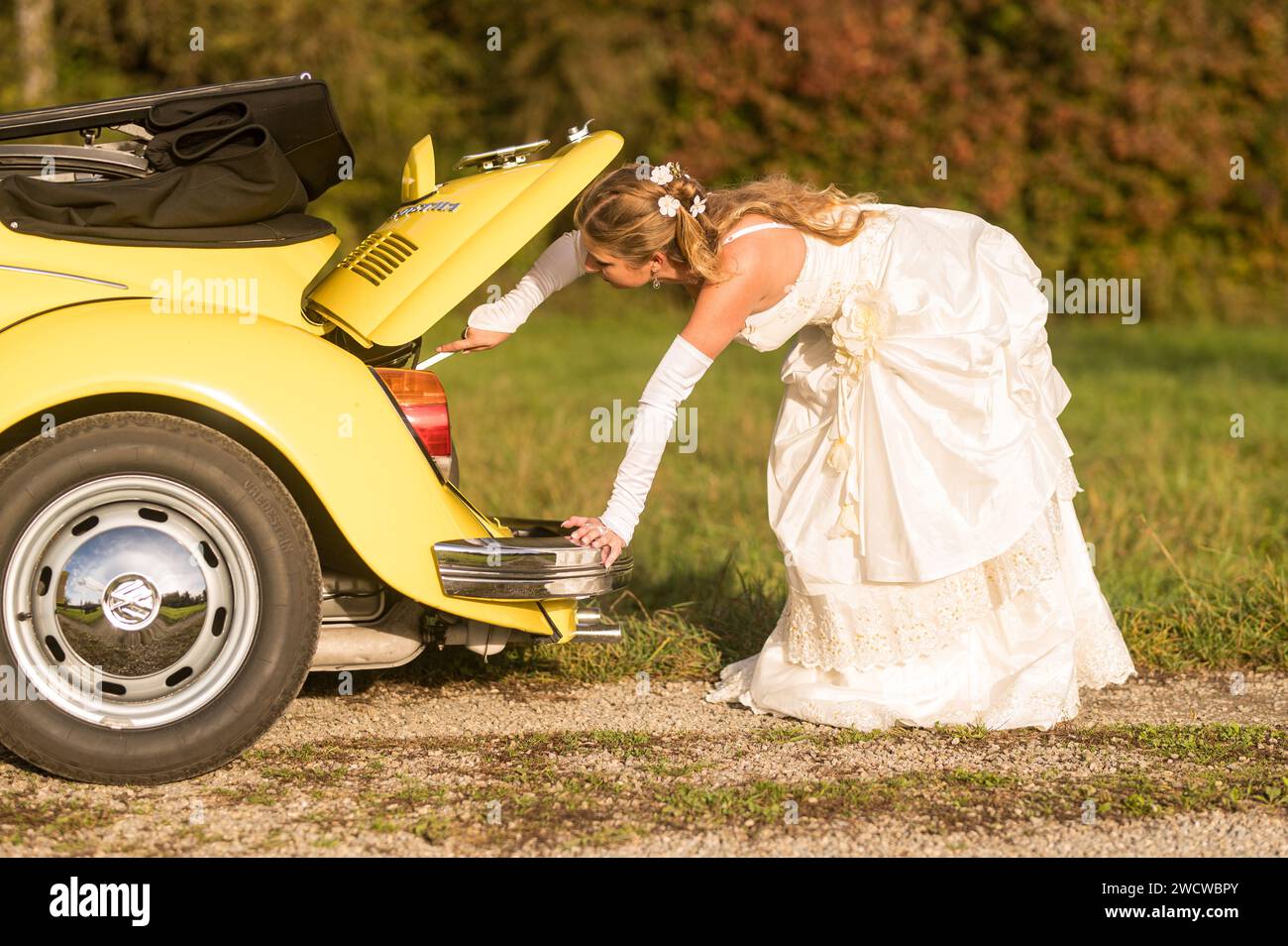 Lustige, ungewöhnliche, stilvolle, originelle Fotos mit Rollenumkehr eines jungen, attraktiven Brautpaares mit wunderschönen Veteranenautos in der Natur. Stockfoto