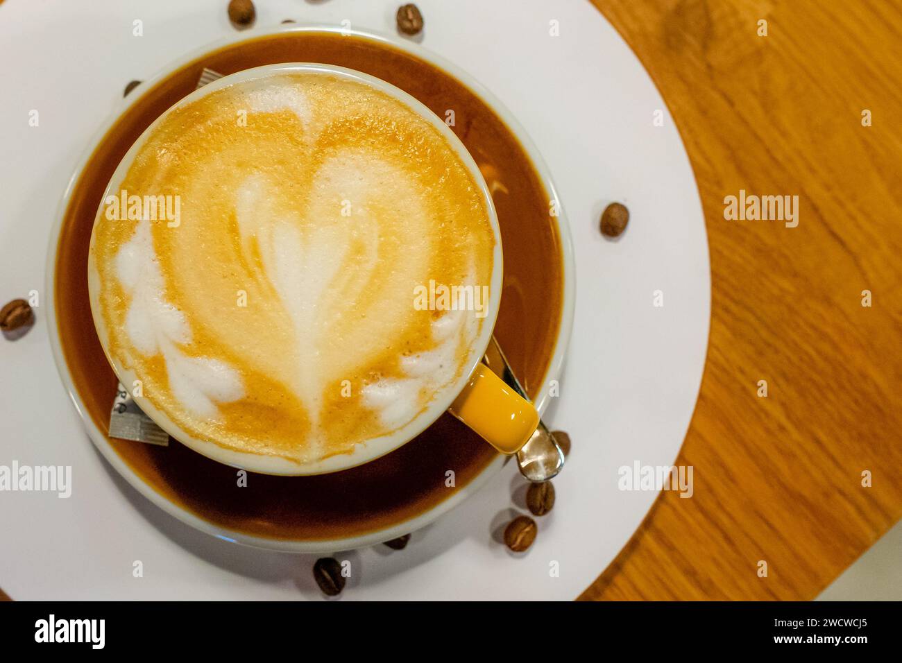 Eine dampfende Tasse frisch gebrühten Kaffees wird elegant in einer makellos weißen Keramikschale präsentiert, die auf einer passenden Untertasse liegt Stockfoto