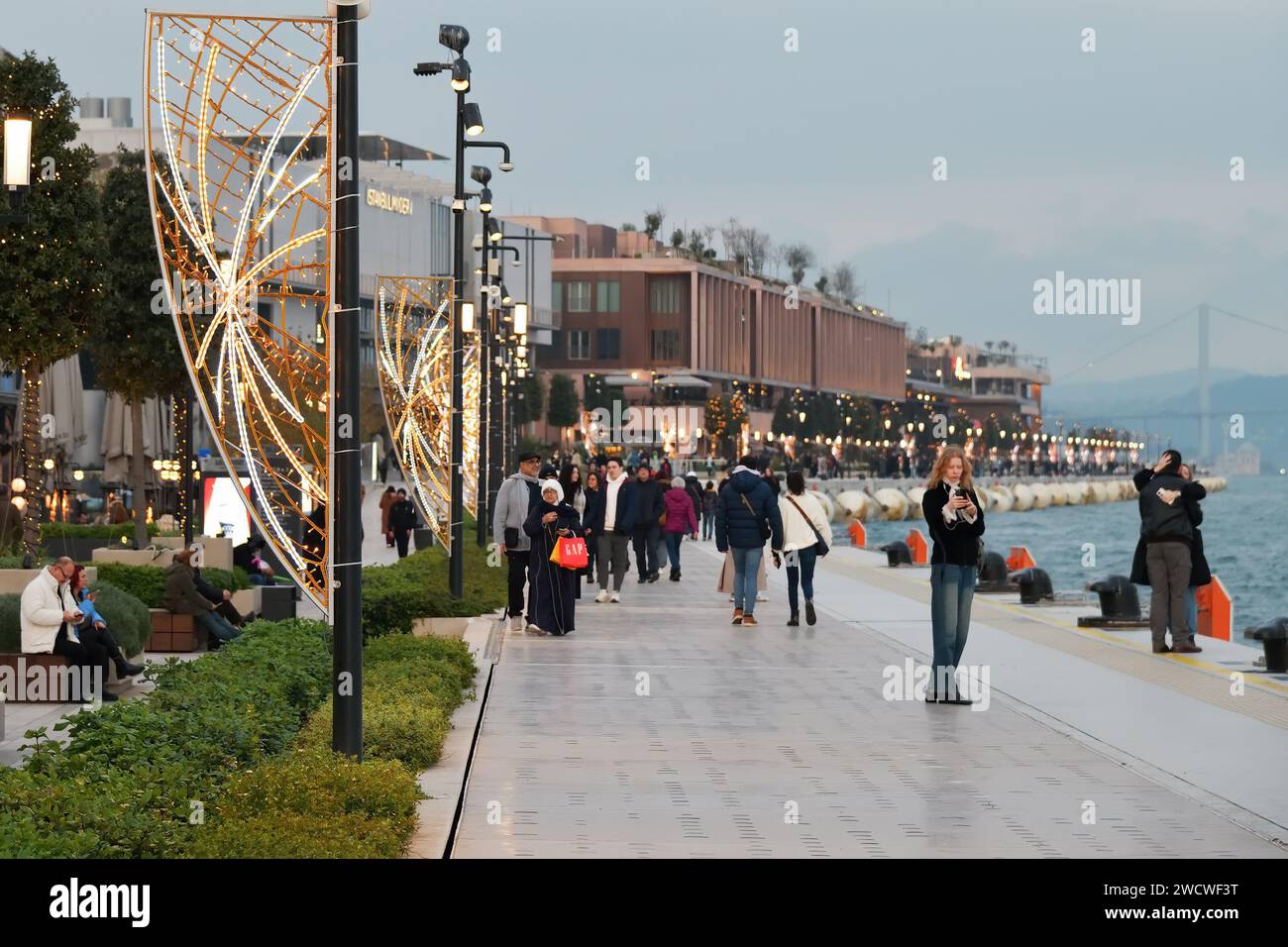 Istanbul, Türkei - 11. Dezember 2023: Die Menschen spazieren abends auf dem Stadtdamm. Galataport Promenade Stockfoto