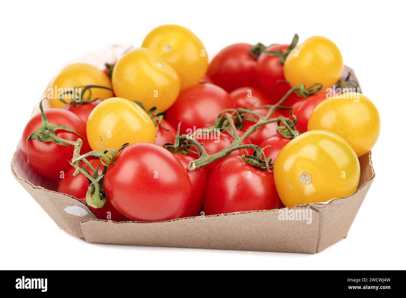 Reife rote und gelbe Tomaten in einem Karton auf weißem Hintergrund. Fokus auf den Vordergrund, Hintergrund unscharf. Kopierbereich. Stockfoto