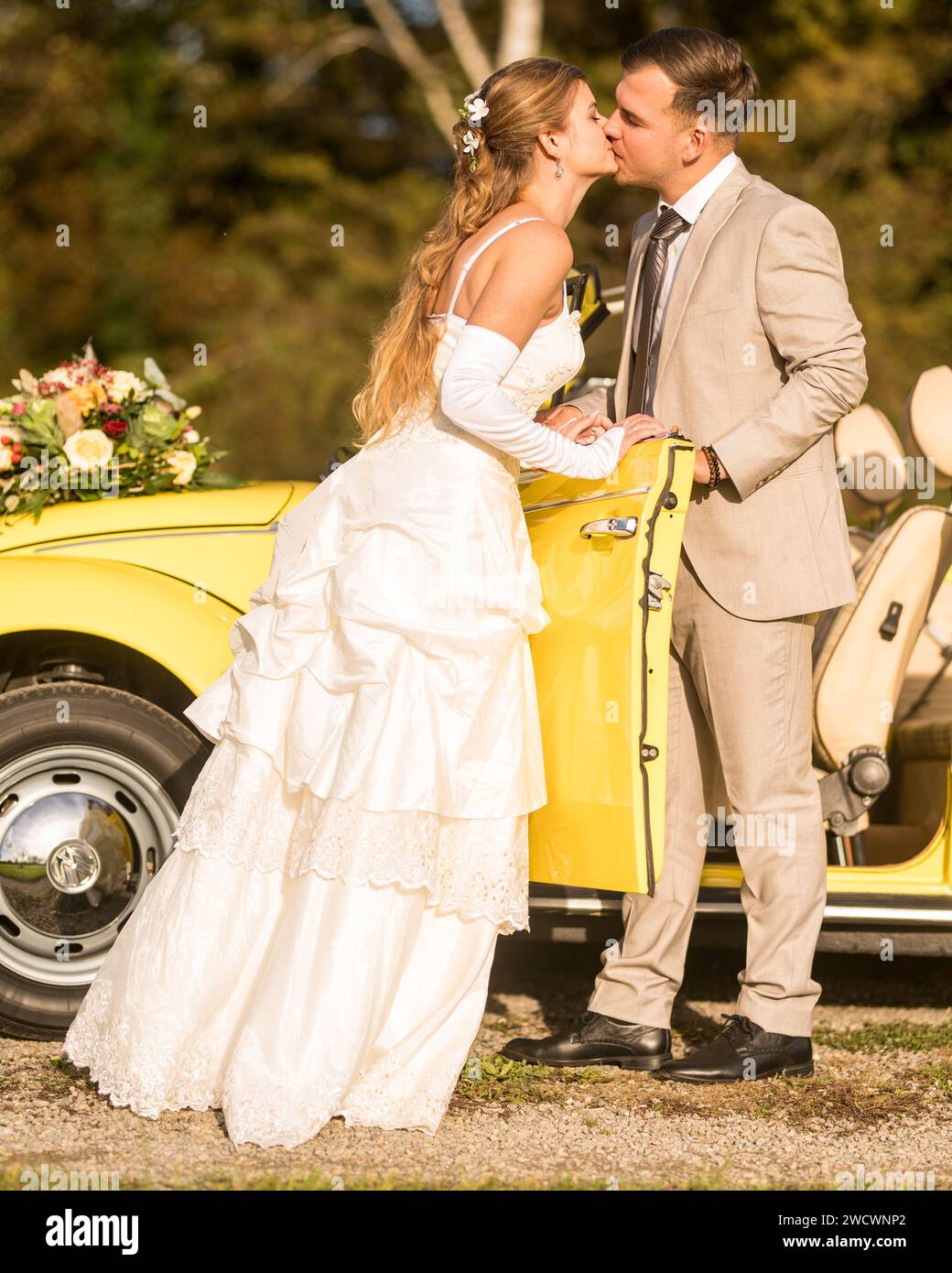 Lustige, ungewöhnliche, stilvolle, originelle Fotos mit Rollenumkehr eines jungen, attraktiven Brautpaares mit wunderschönen Veteranenautos in der Natur. Stockfoto