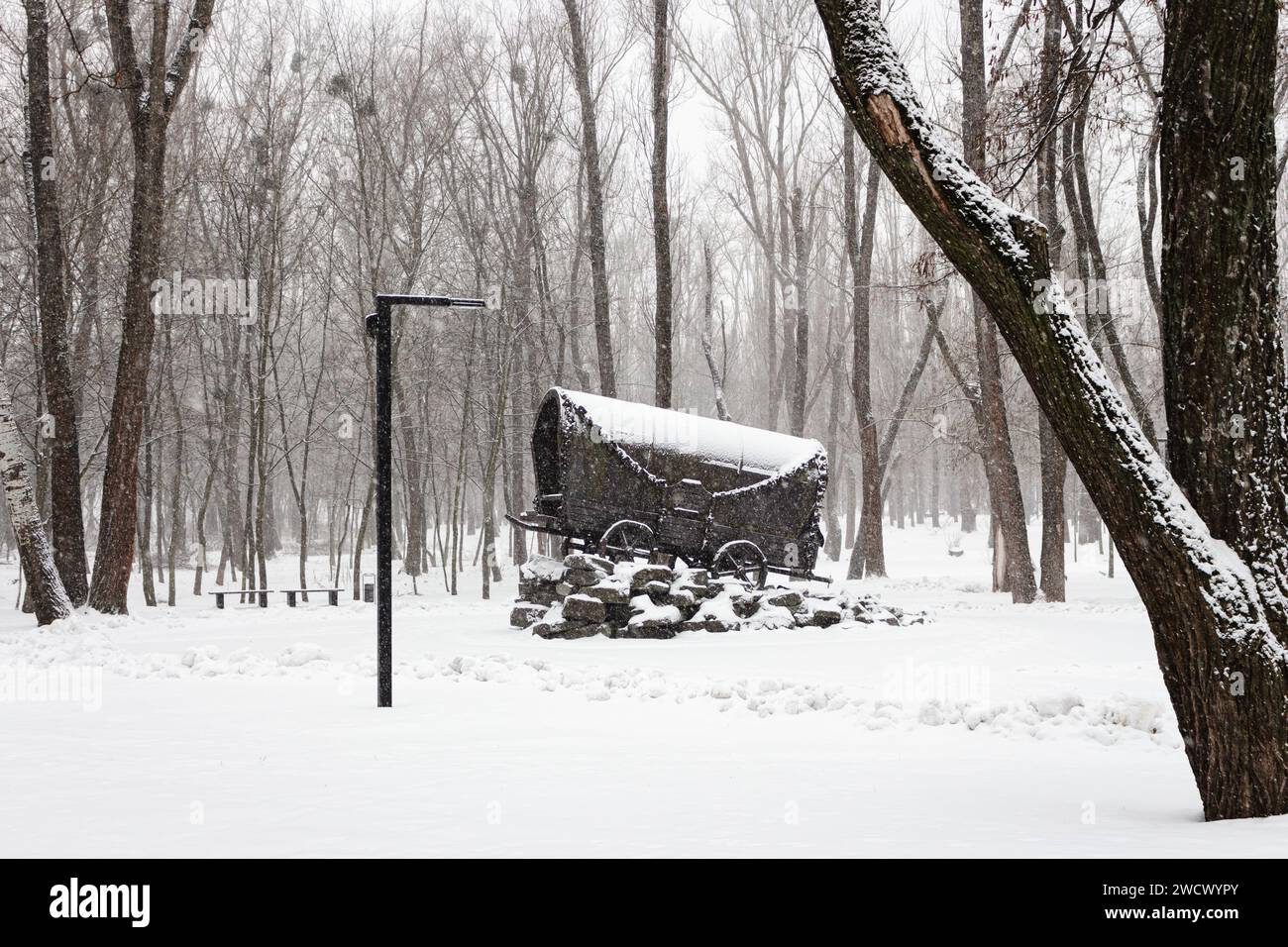 Denkmal des Holocaust der Zigeuner in Babi Jar, Kiew, Ukraine. Zigeunerwagen im Schnee zur Erinnerung an faschistische Opfer. Winterpark im Schneesturm. Wahrzeichen von Kiew. Stockfoto