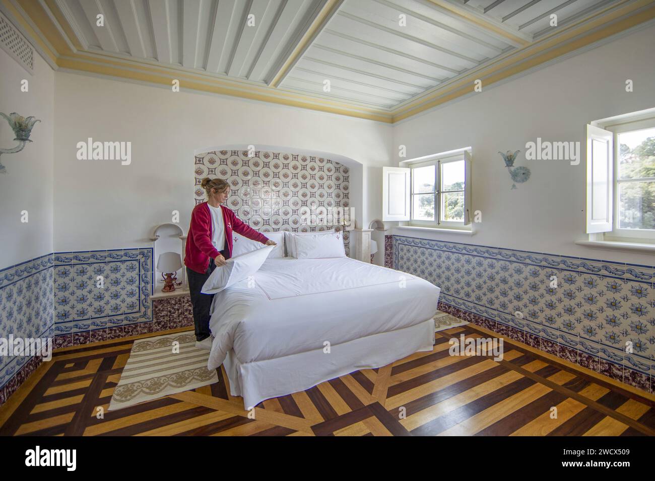 Portugal, Alentejo, Melides, Putzfrau, die das Bett in einer Suite des Vermelho Hotels herstellt, Boutique-Hotel des Schuhdesigners Christian Louboutin, dekoriert mit Azulejos und eingelegten Holzböden Stockfoto