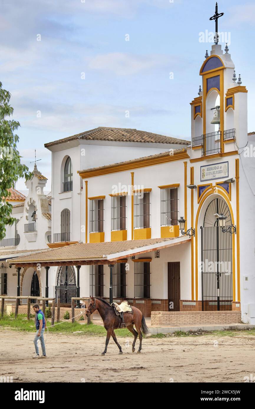 Spanien, Andalusien, El Rocío, Mann, der ein Pferd zieht in einer Sandstraße, gesäumt von Hermandaden, die Häuser katholischer Bruderschaften Stockfoto