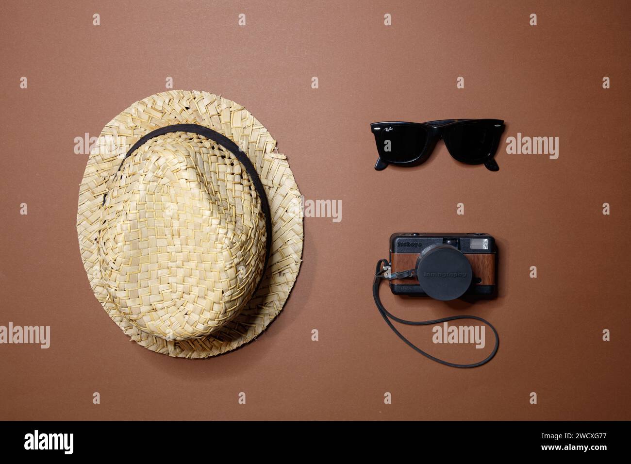 Blick von oben auf einen Strohhut, eine Lomo-Filmkamera und eine Rayban-Sonnenbrille, Studio-Aufnahme Stockfoto