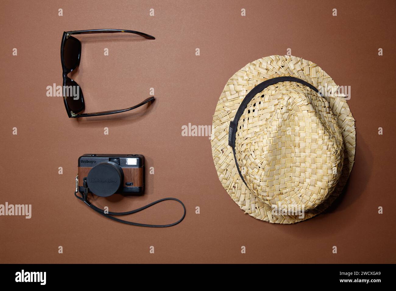 Blick von oben auf einen Strohhut, eine Lomo-Filmkamera und eine Rayban-Sonnenbrille, Studio-Aufnahme Stockfoto