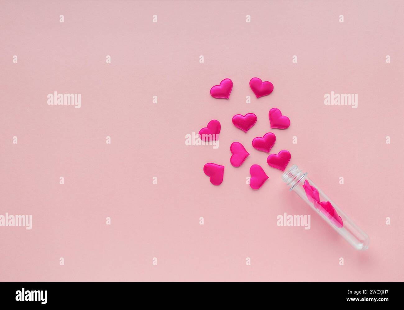 Stoffherzen aus einem Reagenzglas auf rosa Hintergrund. Stockfoto
