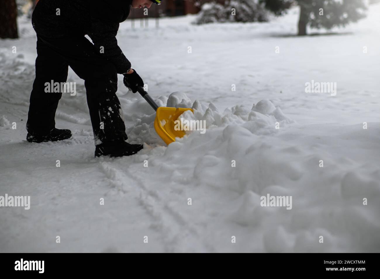Ein Junge schaufelt Schnee nach einem Schneesturm. Stockfoto