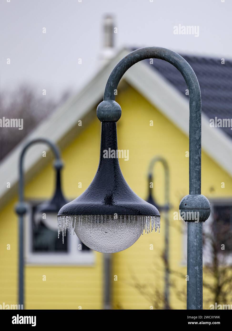 Aufrechte Abbildung einer Straßenlaterne oder Straßenlaterne mit vielen Eiszapfen im Winter bei eisigem Regen und schwarzem Eis Stockfoto