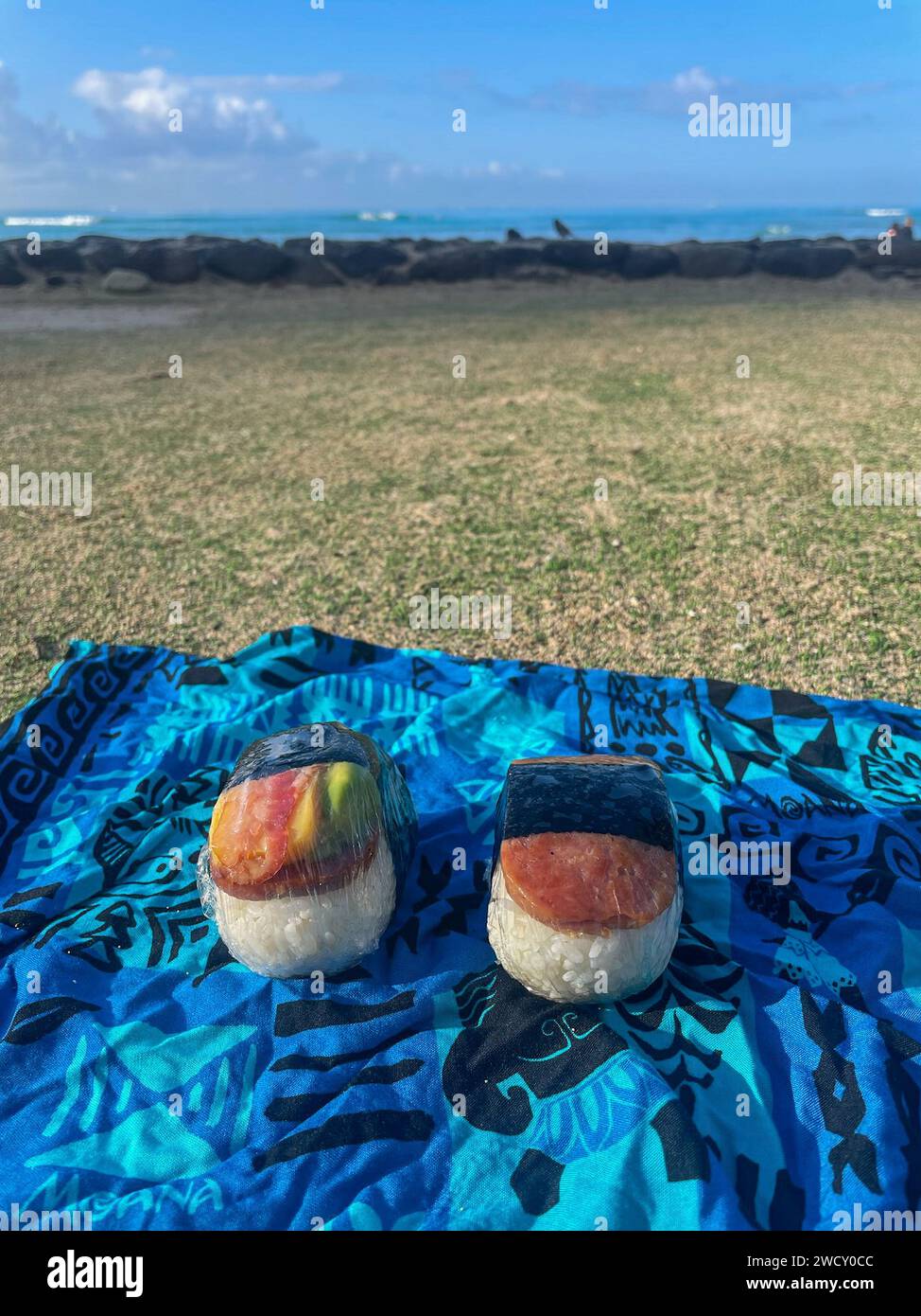 Spam-Musubi auf einem Strandtuch mit Waikiki Strand in der Ferne Stockfoto