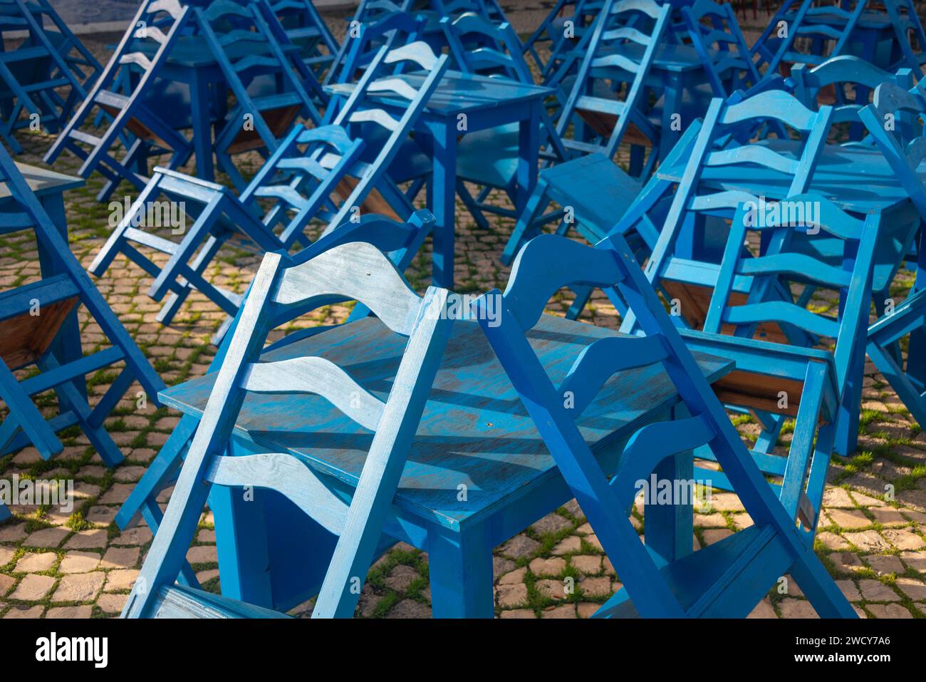 Leere blaue Holztische und -Stühle vor einem Café oder Restaurant, gestapelt. Stockfoto