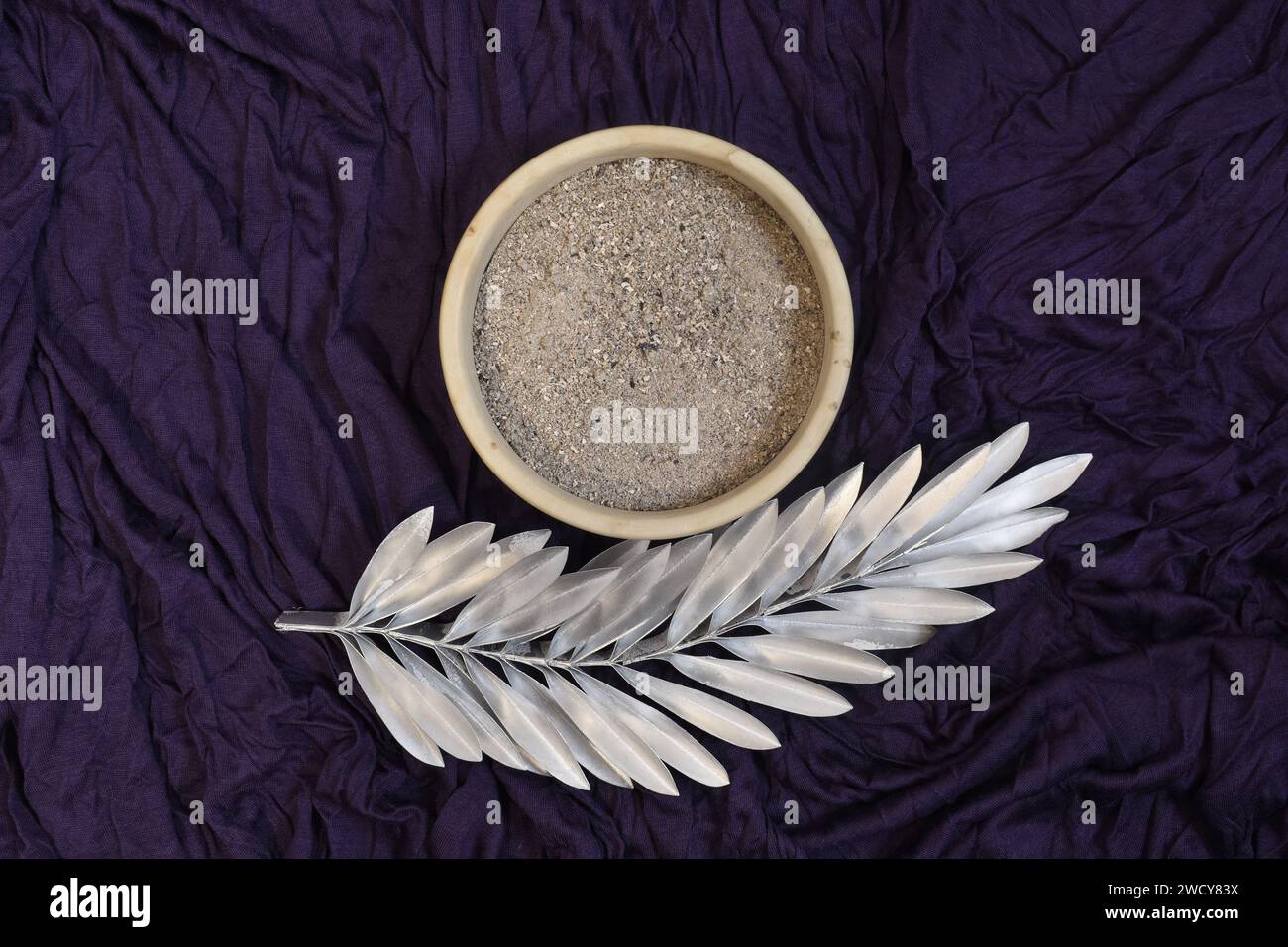 Asche und silbernes Palmenblatt auf violettem Hintergrund. Ash Wednesday-Konzept. Stockfoto