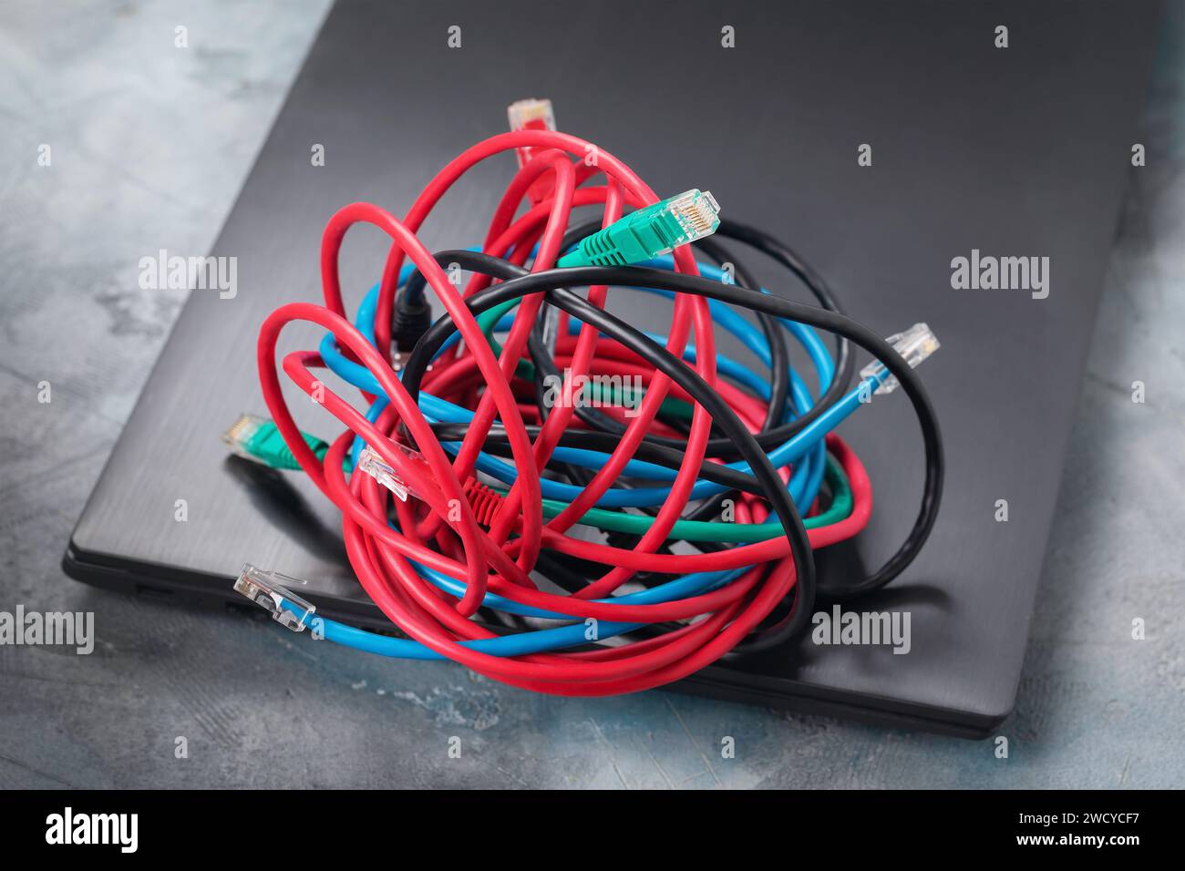 Ein Haufen Netzwerkdrähte auf einem Laptop, ein Konzept zum Thema Verwirrung bei der Verbindung mit einem lokalen Netzwerk oder dem Internet über Kabel und der Übergang Stockfoto