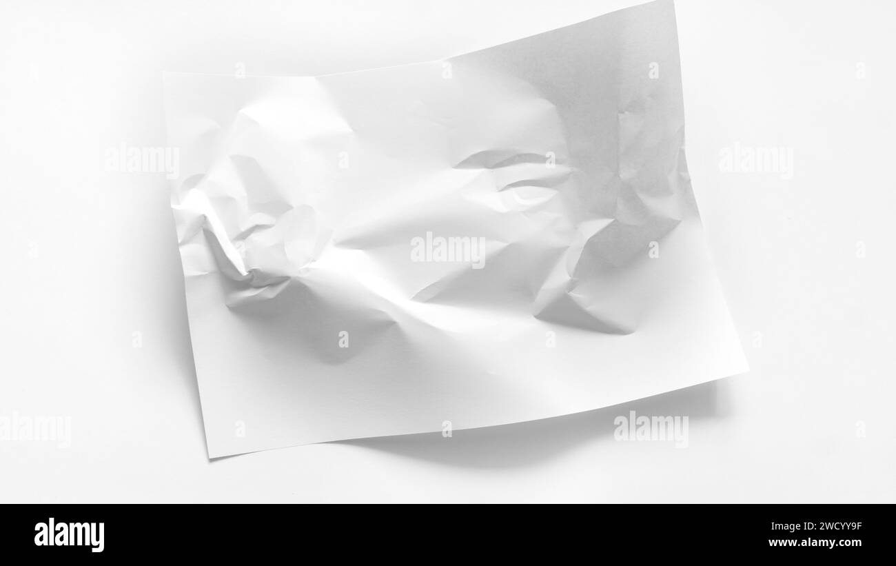Das weiße A4-Blatt ist leicht zerknittert. Ein weißes zerknittertes Blatt Papier liegt in der Mitte eines weißen Hintergrunds mit Kopierraum. Abstrakter weißer Rücken Stockfoto
