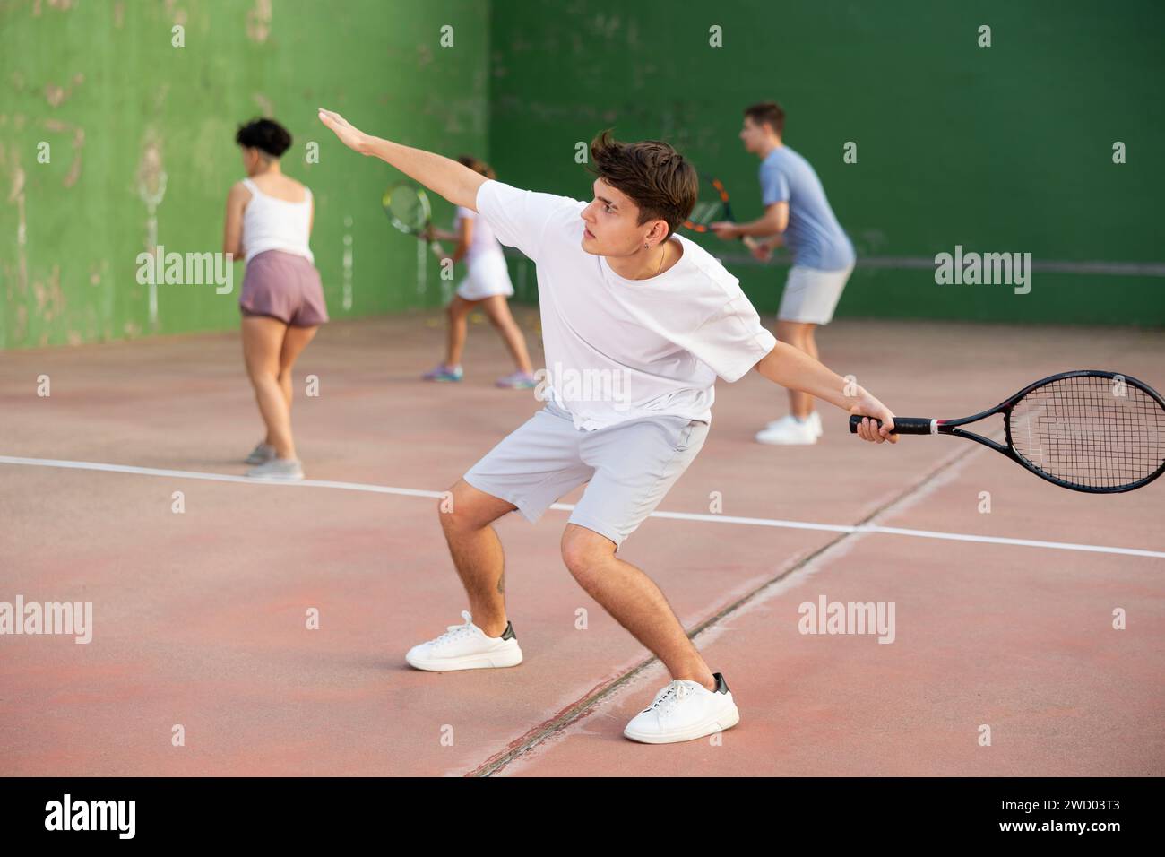 Junger Mann serviert Ball während Frontenis Spiel im Freien Stockfoto